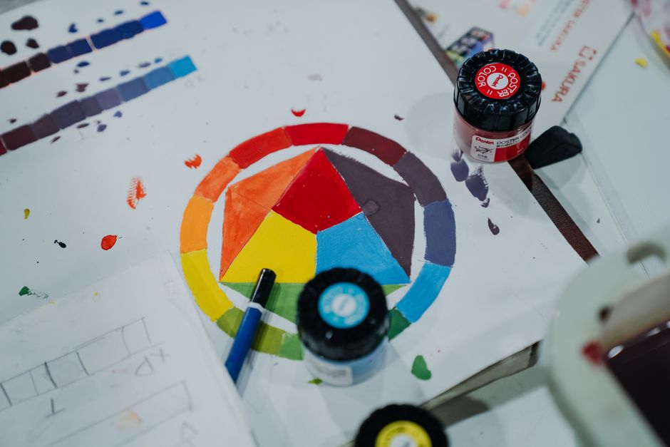 A creative setup with a hand-painted color wheel and paint jars in an artistic workspace.